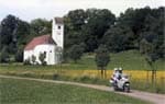 Clem and Sue riding past a church in Austria on Beach's Motorcycle Adventures Classic Alpine Adventure